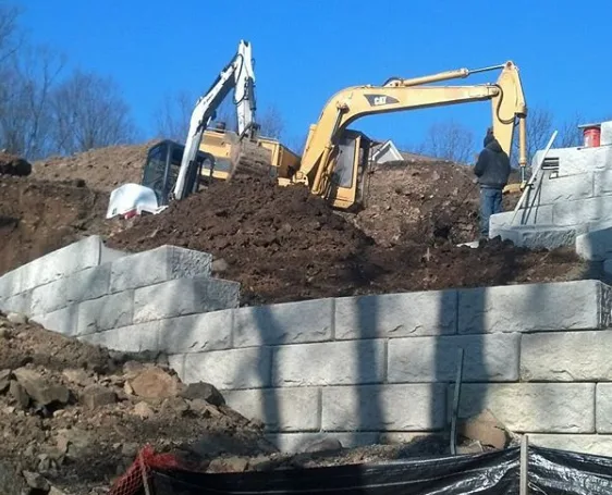 Excavation equipment working behind a retaining wall